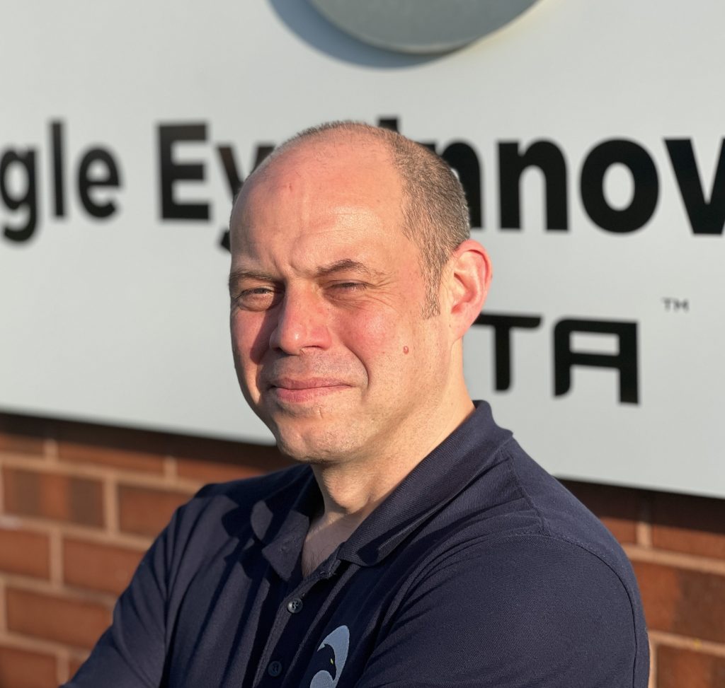 Man in front of white sign on brick wall.