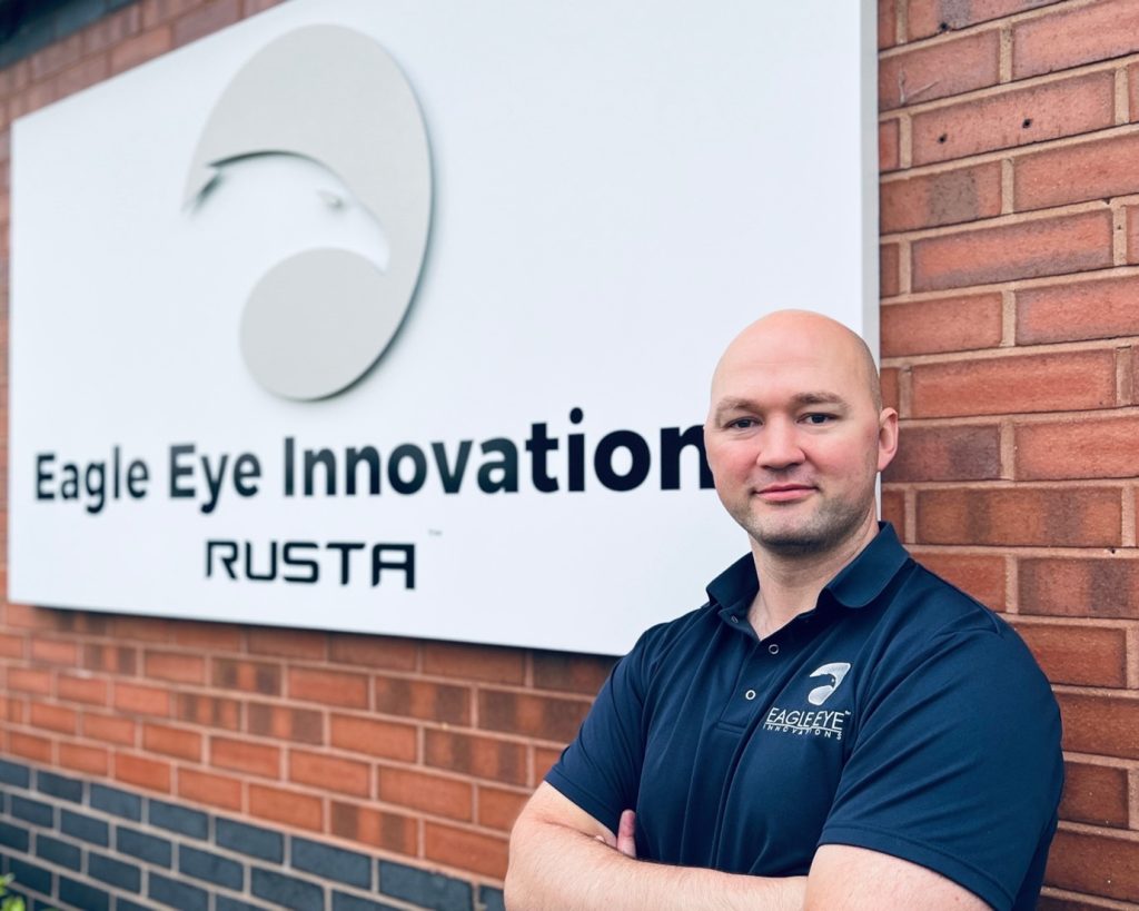 Man stood in front of Eagle Eye Innovations RUSTA sign.