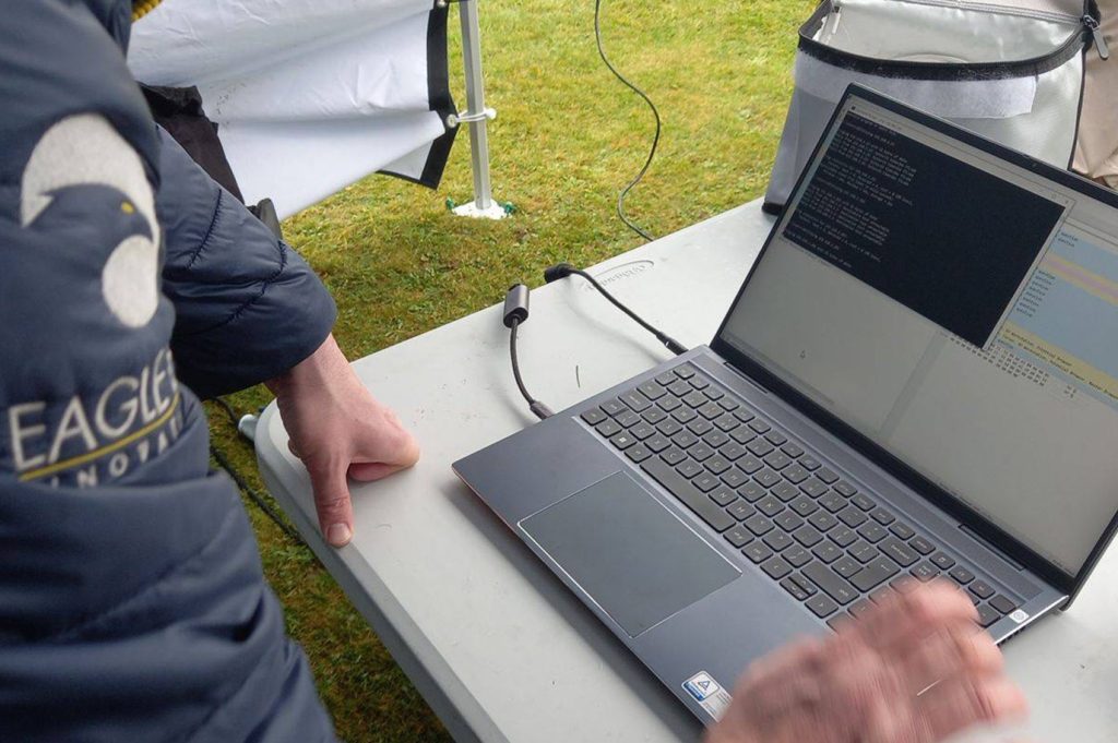 Image of man using laptop in the field as part of a drone consultancy project.