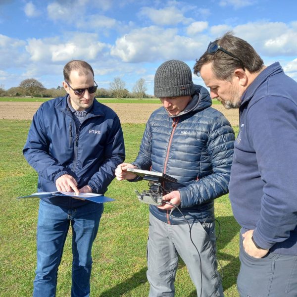 Group of people examining drone controller learning how to fly a drone.