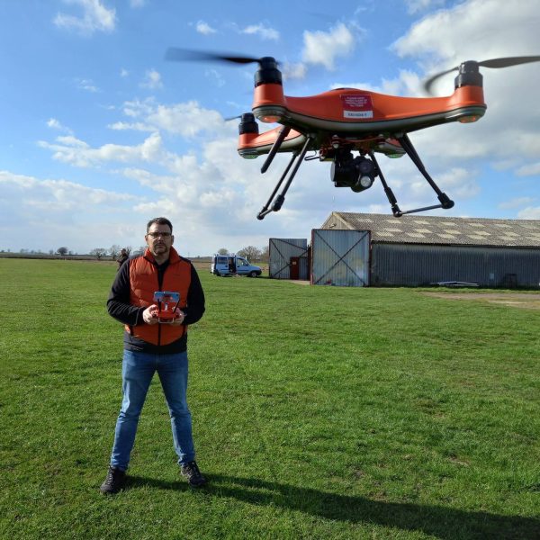 Man flying drone. Drone is in the air in the top right corner of the image.