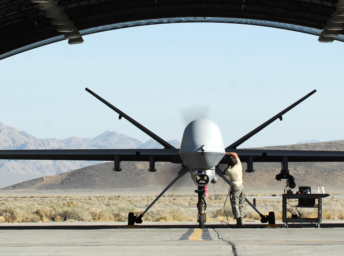Image of Reaper in an outdoor hangar with a man performing repairs.