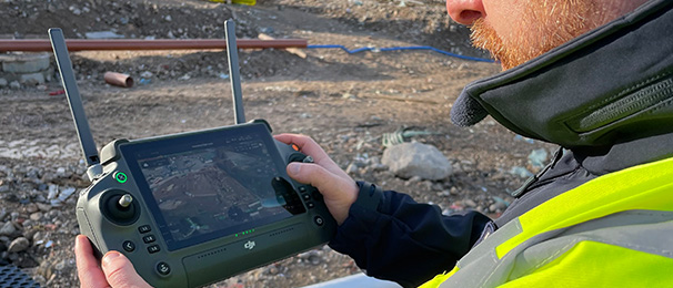Close up of drone controller screen. Man using it on construction site.