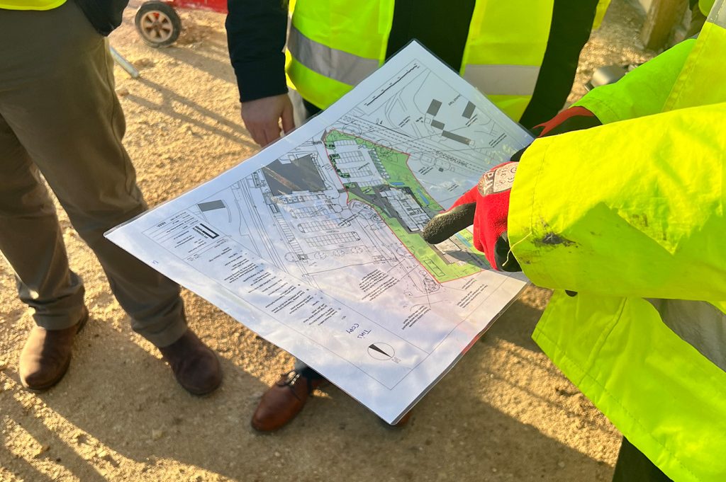 Building plan for a new college. Man is pointing at the map.