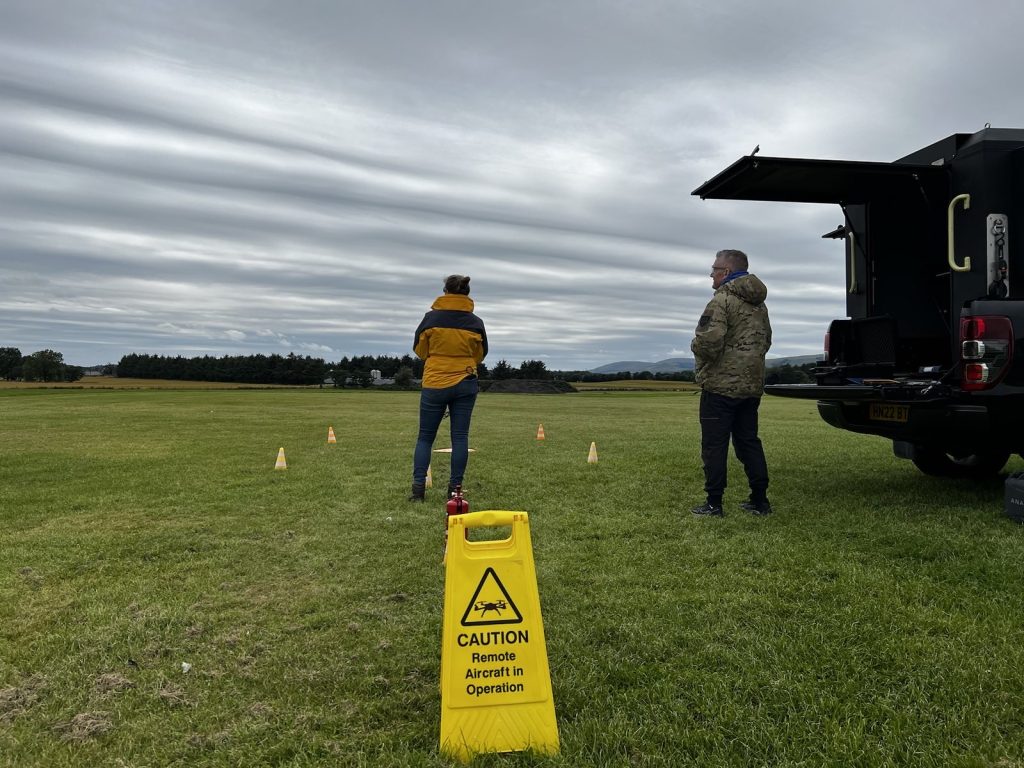 Two people standing in a field flying a drone.